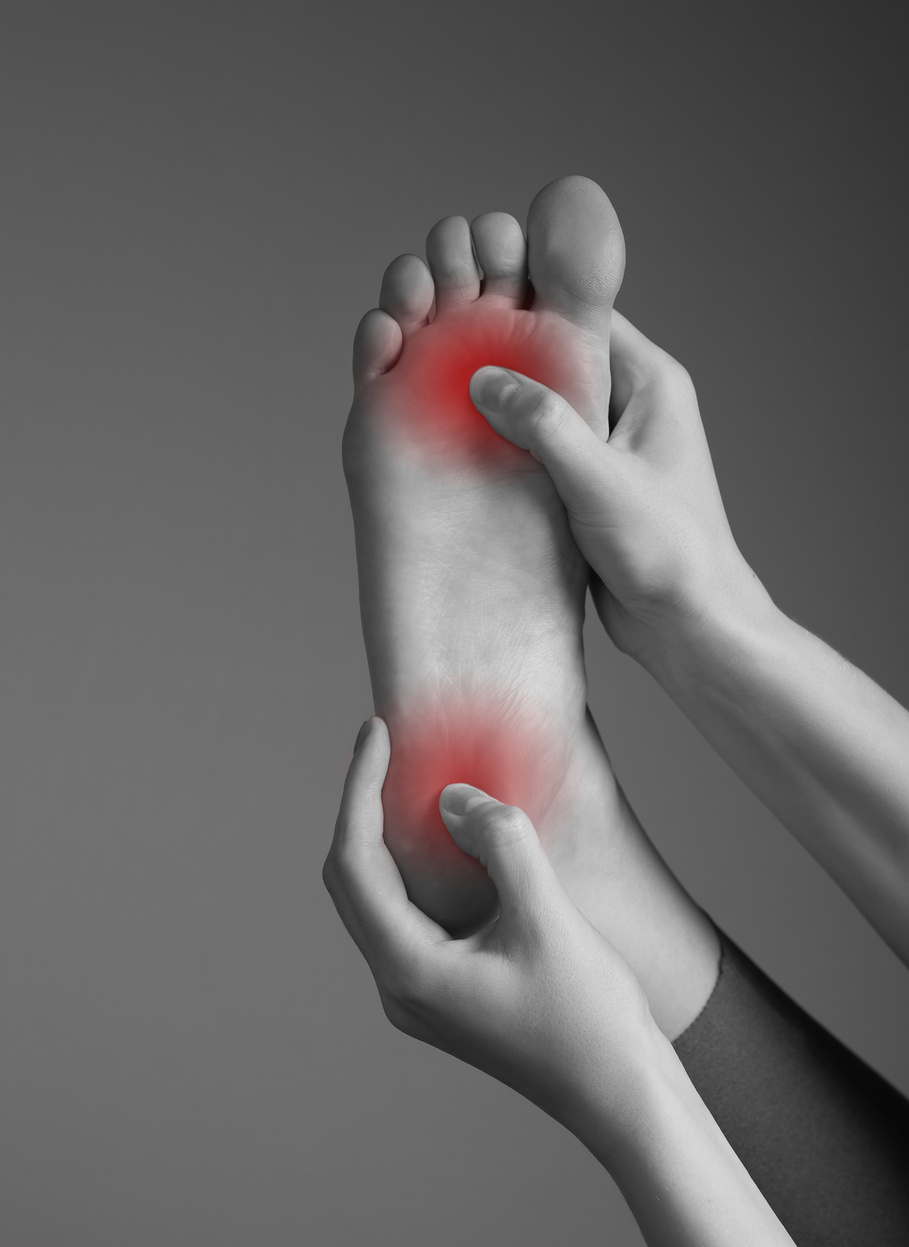 Toe and Heel Pain Caused by Plantar Fasciitis, Arthritis, Diabetes, Tendinitis, Spurs, Bruise, Fracture. Woman Hands Holding Foot with Red Spot. Black and White.